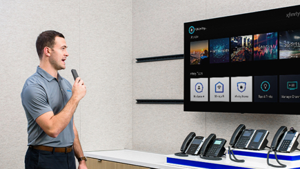 an employee giving a product demo, using a TV and business phones.